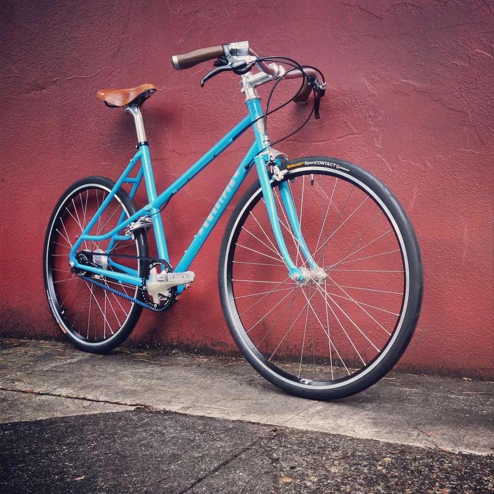 THE A-LINE. A step-through suggests carefree pedaling in skirts under a sunshiny sky where birds are constantly chirping your favorite song. Clocking in at just 22 pounds, and equipped with a modern component group, it is ready for both a slow picnic in the park to a fast haul into work.